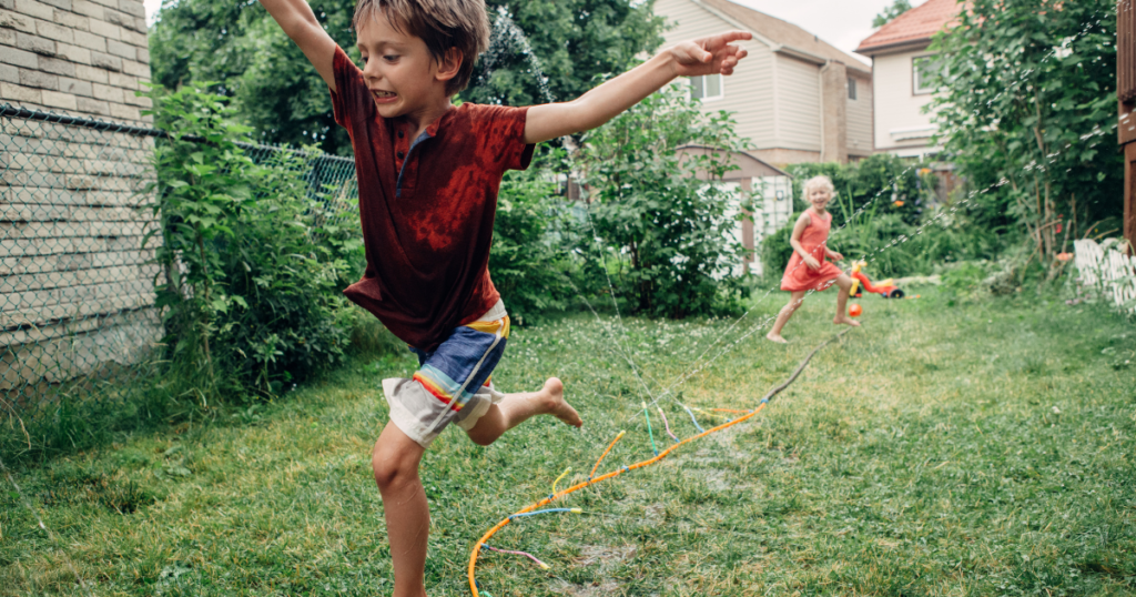 children running through a sprinkler