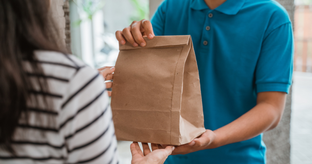 delivery person handing a grocery bag