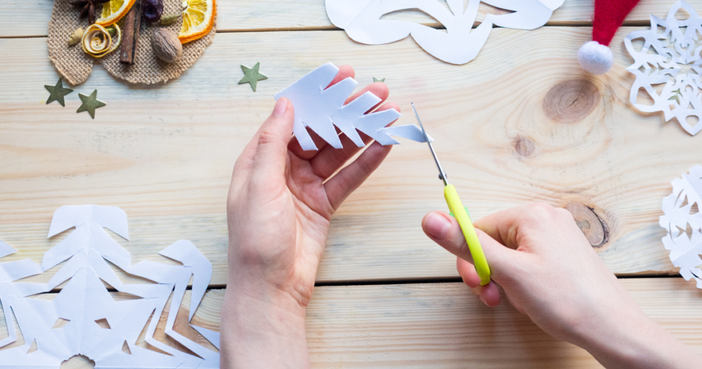 person cutting paper snowflakes